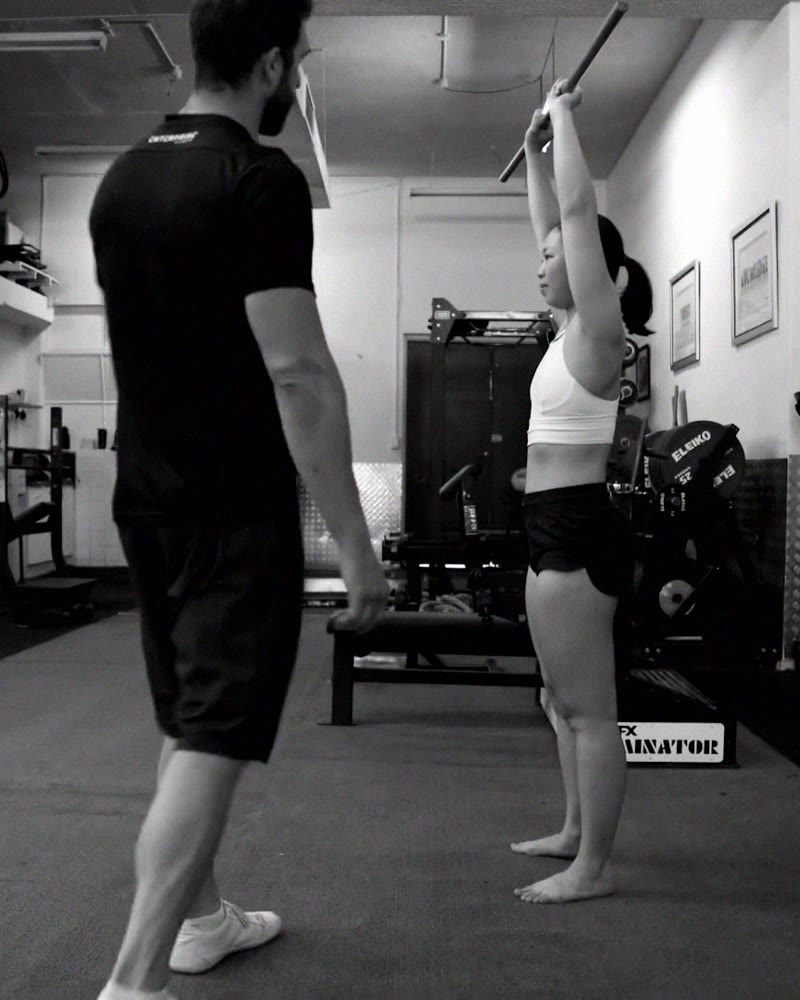 Mark Ottobre watching a client perform the overhead squat test in the Enterprise Fitness studio